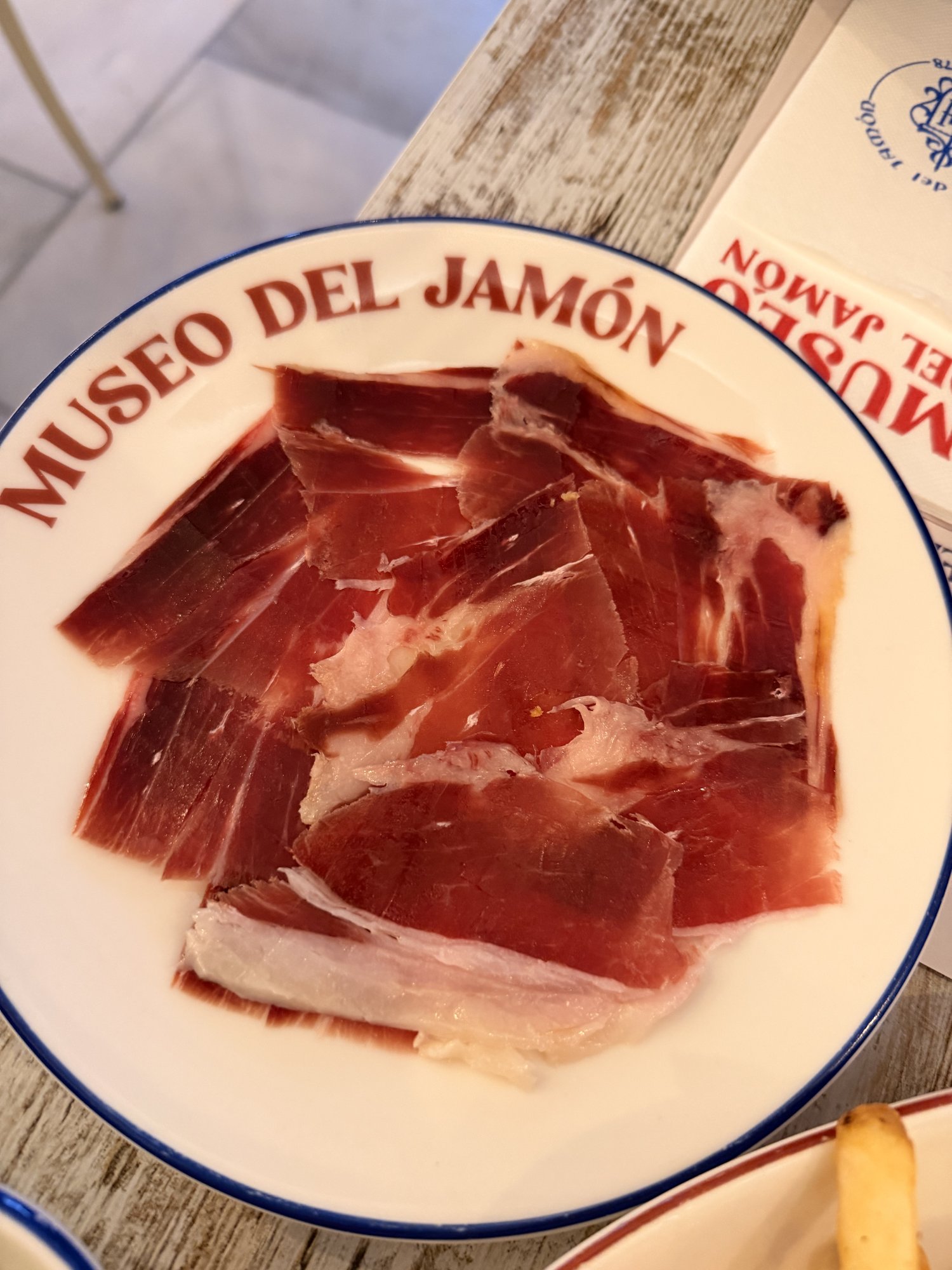 A plate rimmed with 'Museo del Jamón' holding thin slices of marbled Ibérico ham