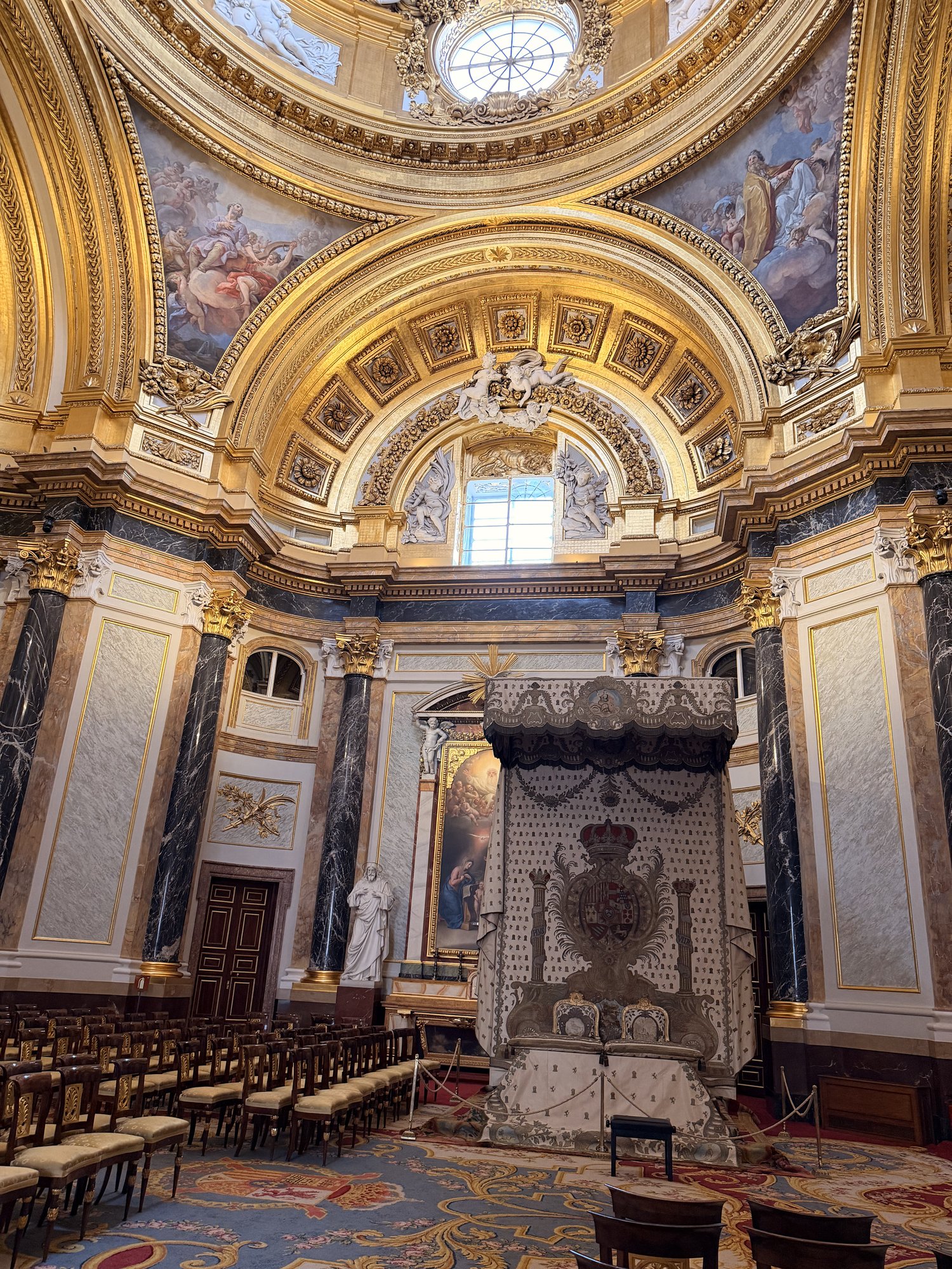 The Royal Chapel inside the Royal Palace of Madrid with dark marble columns, gilded arches, and a frescoed dome
