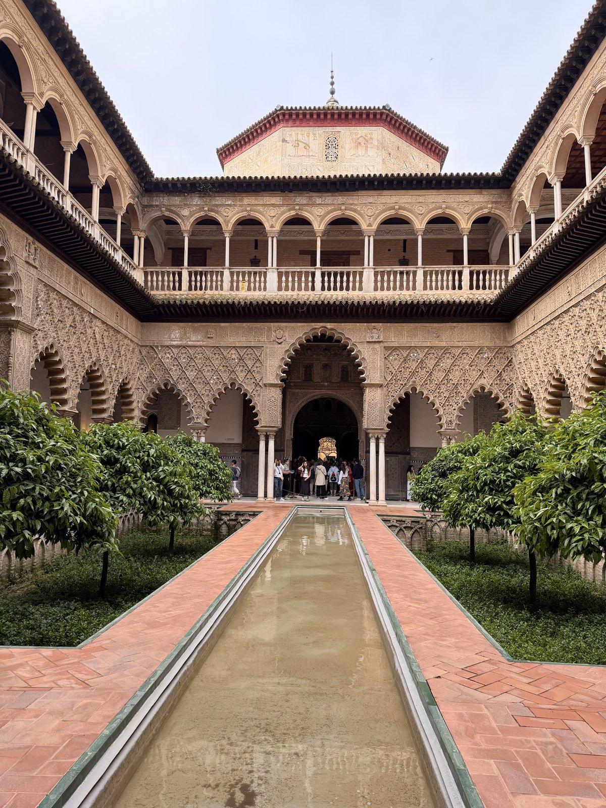 The Patio de las Doncellas courtyard at the Royal Alcázar with a long reflecting pool and arched galleries