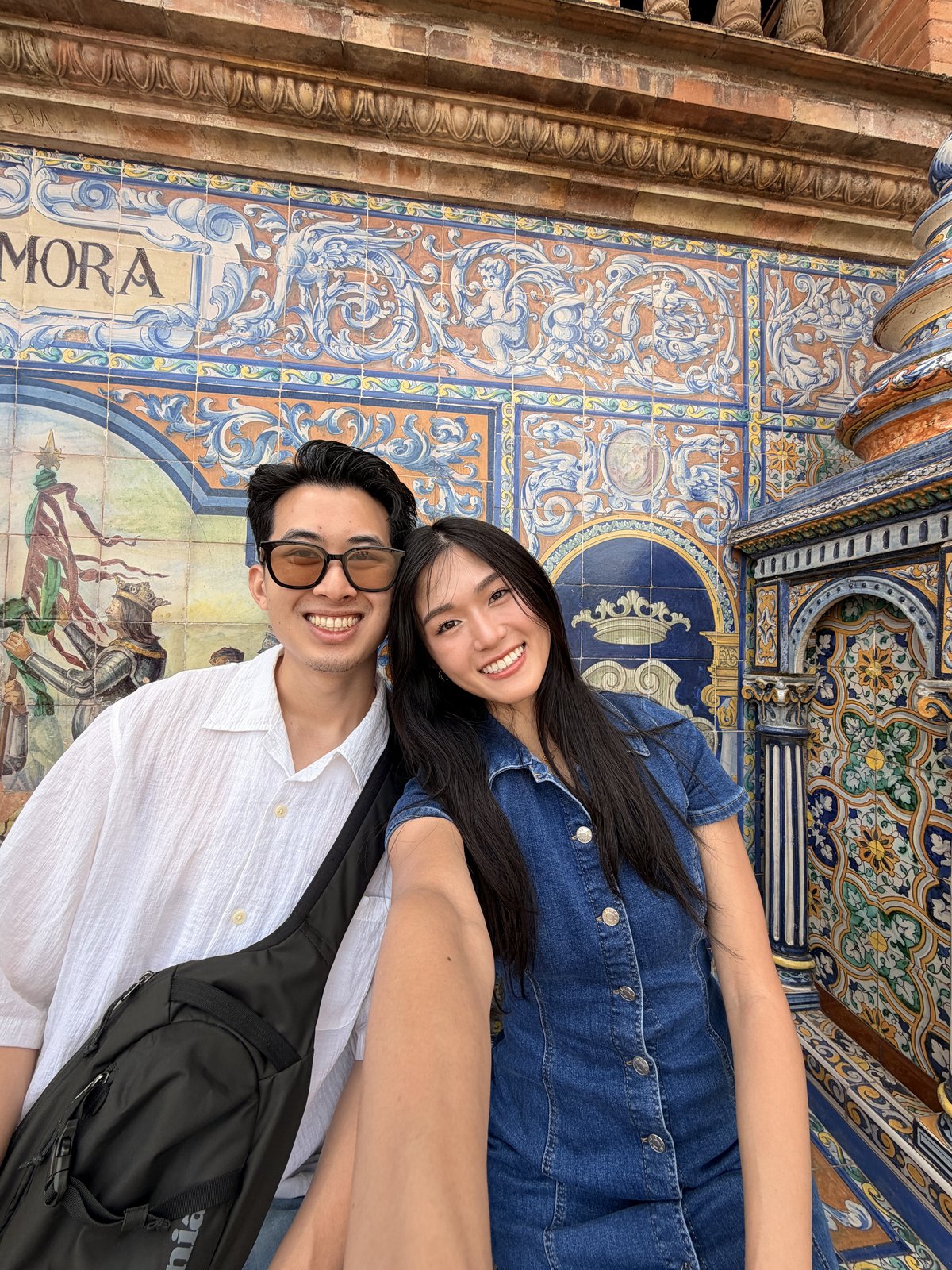 Couple in front of the hand-painted province alcove tilework at Plaza de España